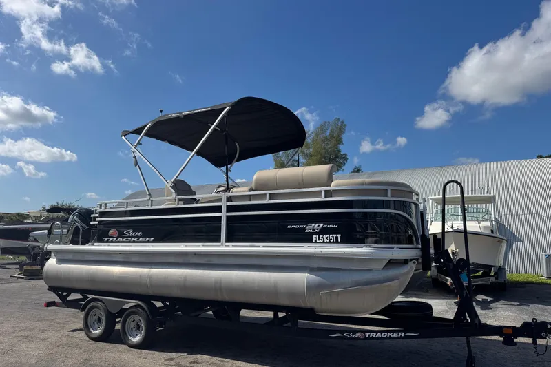 The Image of 2024 Sun Tracker SportFish 20 DLX pontoon boat on trailer under blue sky. - 0