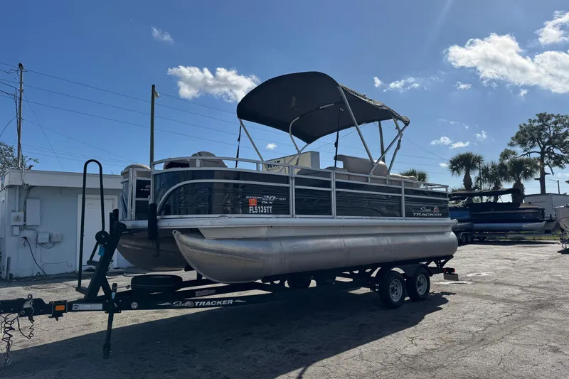 Slide: The Image of 2024 Sun Tracker SportFish 20 DLX pontoon boat on trailer under clear sky. - 2