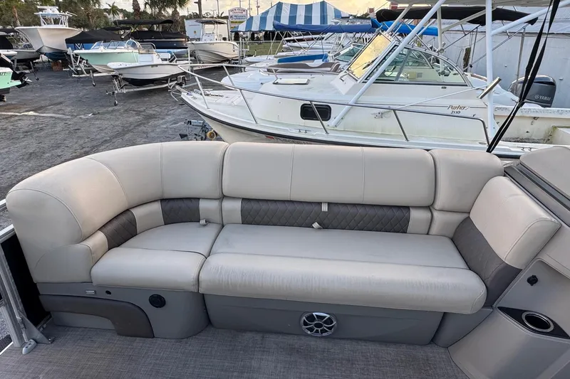 Slide: The Image of 2024 Sun Tracker SportFish 20 DLX pontoon boat with comfortable seating, docked among other boats. - 21