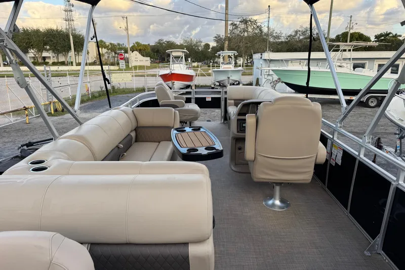 Slide: The Image of 2024 Sun Tracker SportFish 20 DLX pontoon boat interior with beige seating and table. - 4