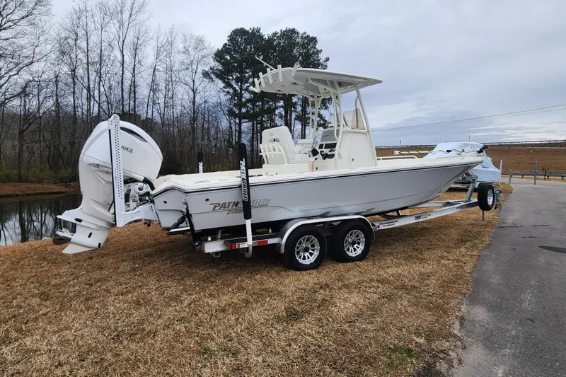 Slide: The Image of 2024 Pathfinder 2600 TRS boat on trailer near a pond, side view. - 2