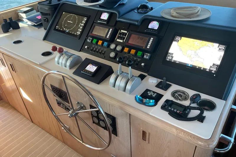 Slide: The Image of 1997 Hatteras 70 Sport Deck Motor Yacht helm with navigation controls and steering wheel. - 14