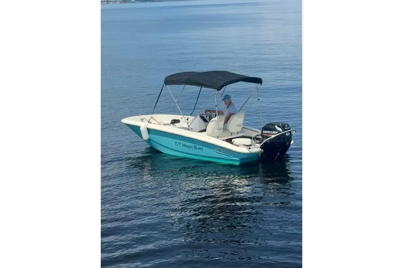 Slide: The Image of Small motorboat "T/T Moon River" with canopy on calm water, featuring a Mercury 40 engine. - 51