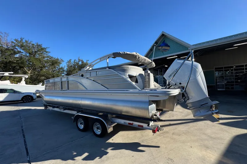 Slide: The Image of 2026 Bennington 23 LTFB pontoon boat on trailer, parked outdoors under clear blue sky. - 16
