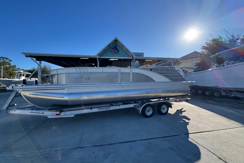 Slide: The Image of 2026 Bennington 23 LTFB pontoon boat on trailer under clear blue sky. - 2