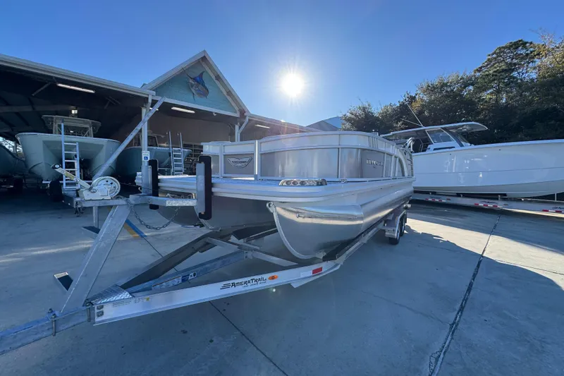 Slide: The Image of 2026 Bennington 23 LTFB pontoon boat on trailer, parked outdoors under clear sky. - 4