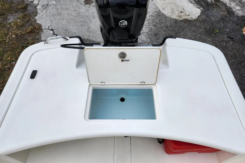 Slide: The Image of 2024 Mako Pro Skiff 17 CC boat with open storage compartment and visible outboard motor. - 16