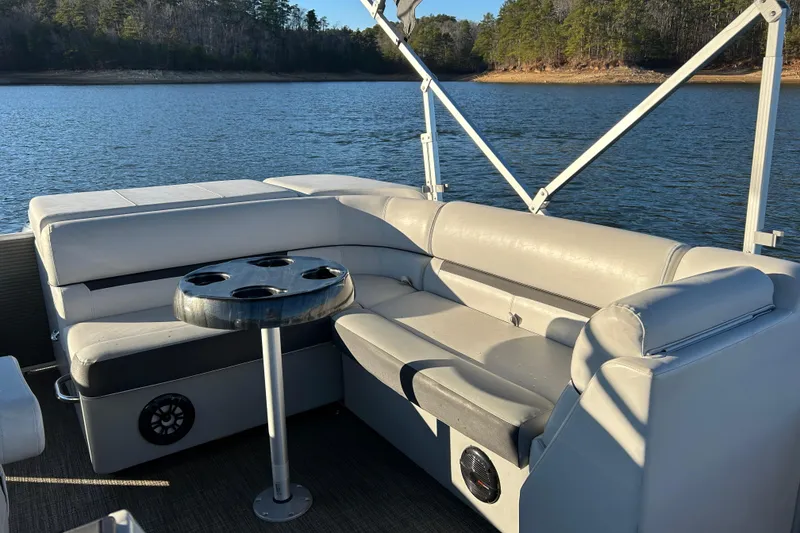 Slide: The Image of 2023 Godfrey Sweetwater 2286 C pontoon boat interior with seating and cup holders on a lake. - 14