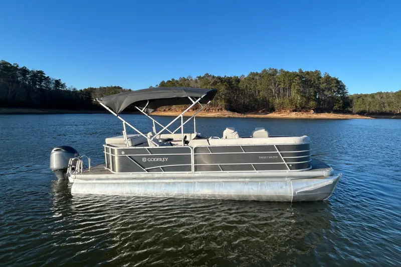 Slide: The Image of 2023 Godfrey Sweetwater 2286 C pontoon boat on a serene lake. - 5
