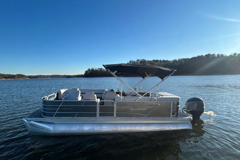 Slide: The Image of 2023 Godfrey Sweetwater 2286 C pontoon boat on a serene lake. - 9
