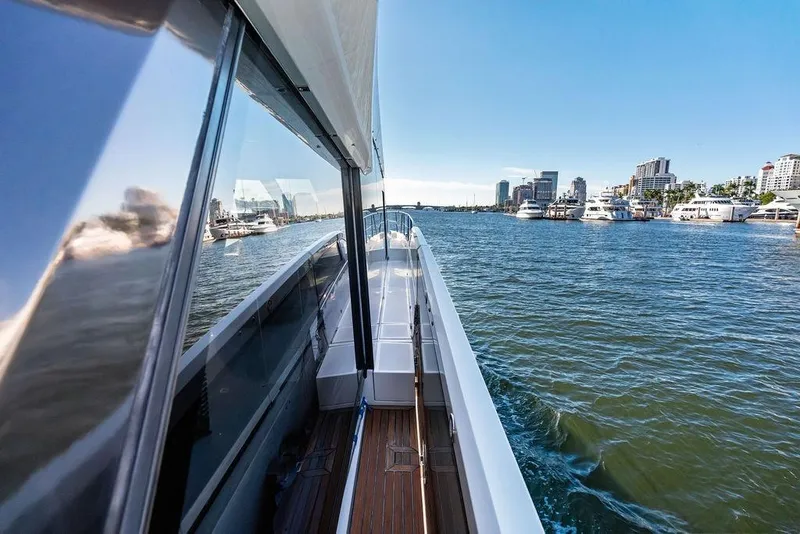 Slide: The Image of 2018 Galeon 640 Fly yacht cruising near city marina, reflecting skyline on water. - 26