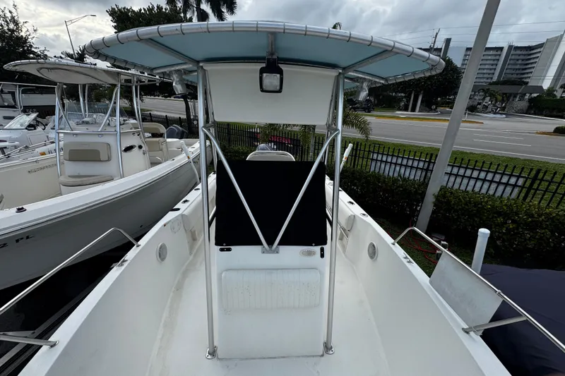 Slide: The Image of 2023 Hydra-Sports 212 CC boat with T-top, docked near a road and buildings. - 13