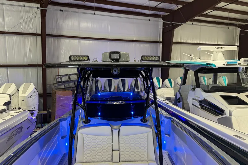 Slide: The Image of 2025 Nor-Tech 390 Sport Center Console boat with illuminated interior in a showroom. - 32