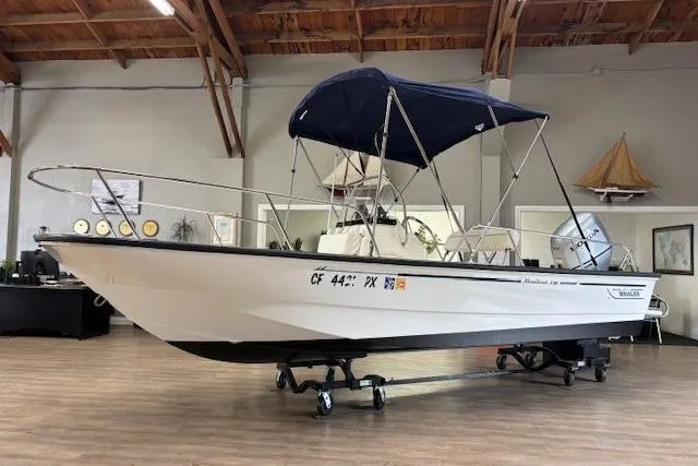 Slide: The Image of 2003 Boston Whaler 170 Montauk boat with blue canopy in indoor showroom. - 4