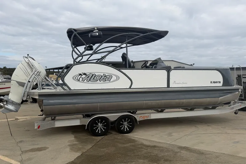 The Image of 2023 Aloha Pontoon PS 260 TT on trailer, parked outdoors under cloudy sky. - 0