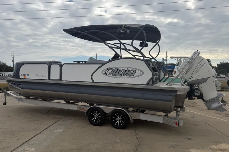 Slide: The Image of 2023 Aloha Pontoon PS 260 TT on trailer, featuring sleek design and Mercury outboard motor. - 1