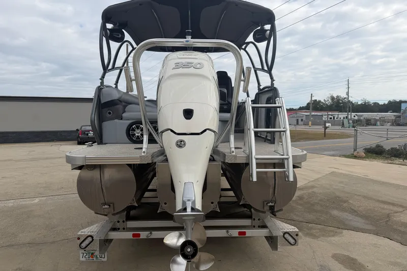 Slide: The Image of 2023 Aloha Pontoon PS 260 TT with powerful outboard motor and ladder, parked outdoors. - 107
