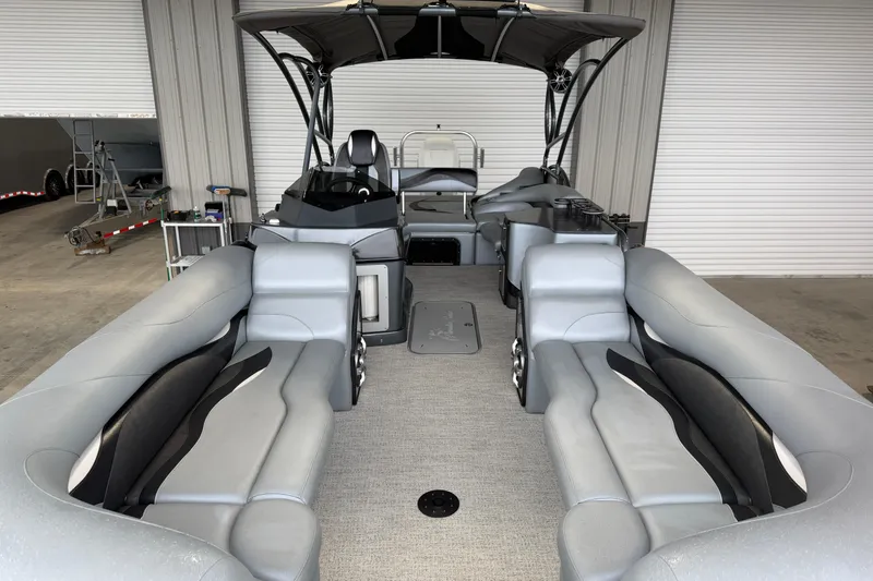Slide: The Image of 2023 Aloha Pontoon PS 260 TT with spacious seating and modern design in a garage setting. - 27