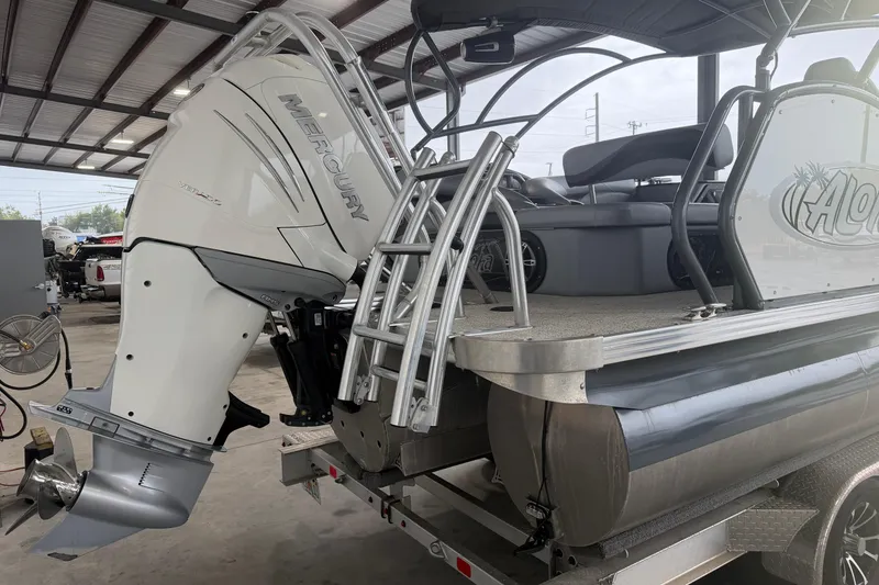 Slide: The Image of 2023 Aloha Pontoon PS 260 TT with Mercury outboard motor in a covered storage area. - 3