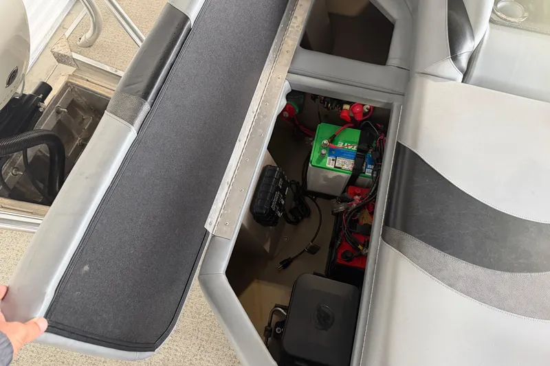 Slide: The Image of 2023 Aloha Pontoon PS 260 TT storage compartment with battery and wiring visible. - 39