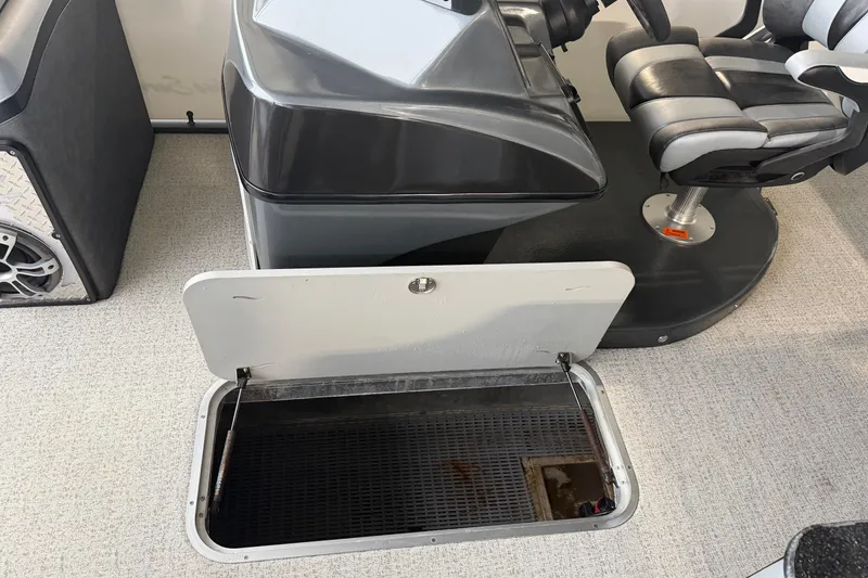 Slide: The Image of 2023 Aloha Pontoon PS 260 TT interior with open storage compartment and captain's chair. - 71