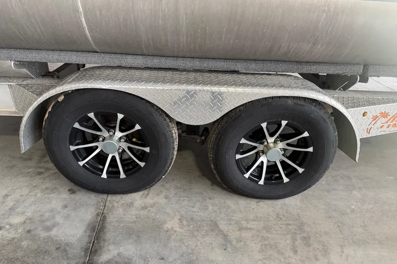 Slide: The Image of 2023 Aloha Pontoon PS 260 TT trailer with dual black alloy wheels on concrete floor. - 8