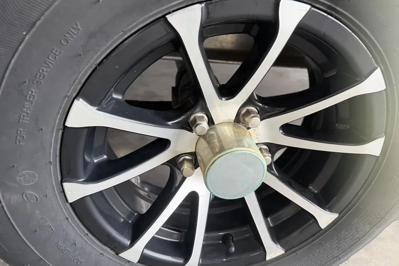 Slide: The Image of Close-up of a 2023 Aloha Pontoon PS 260 TT wheel with black and silver spokes. - 9