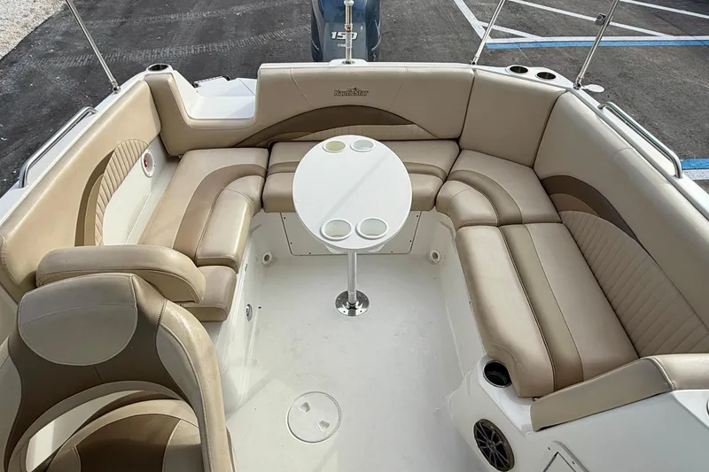 Slide: The Image of 2014 NauticStar 223DC Sport Deck interior with beige seating and round table. - 23