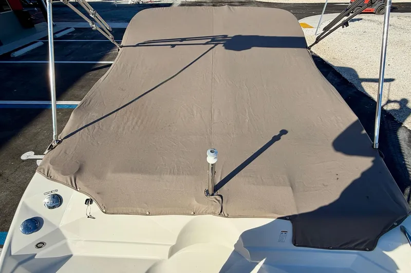 Slide: The Image of 2014 NauticStar 223DC Sport Deck boat with protective cover in a parking area. - 31