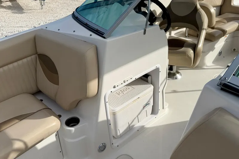 Slide: The Image of 2014 NauticStar 223DC Sport Deck interior with beige seating and built-in cooler. - 38