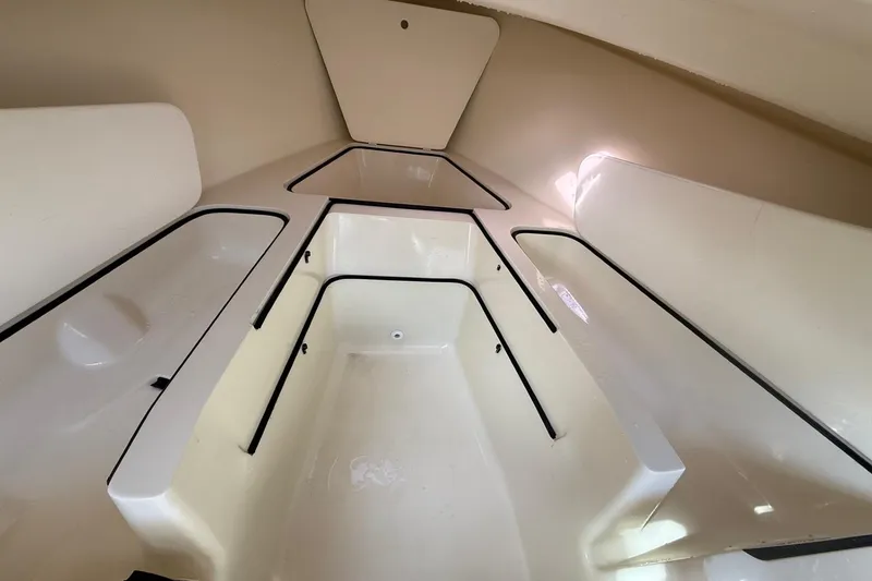 Slide: The Image of Interior of a 2004 Holby Pilot 19 boat, featuring sleek, white storage compartments. - 11