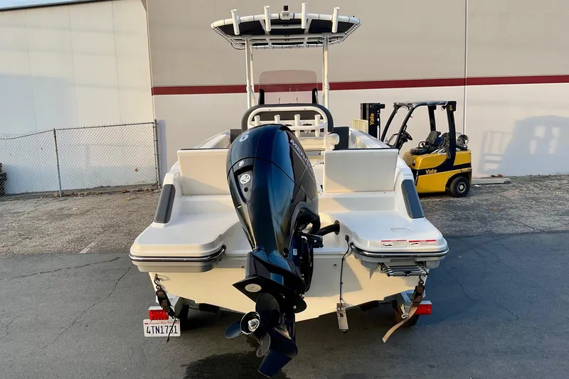 Slide: The Image of 2021 Bayliner Trophy T20CC boat with outboard motor, parked near a warehouse. - 3