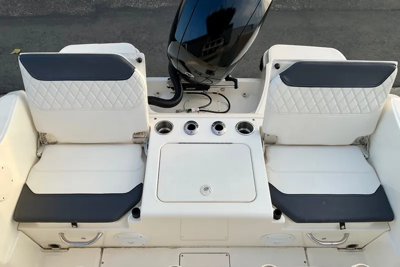 Slide: The Image of 2021 Bayliner Trophy T20CC boat seating and engine area, featuring dual seats and cup holders. - 8