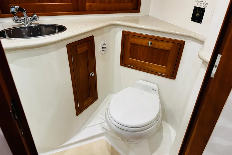 Slide: The Image of 2015 MJM 36z Express yacht bathroom with sink, toilet, and wooden cabinetry. - 22