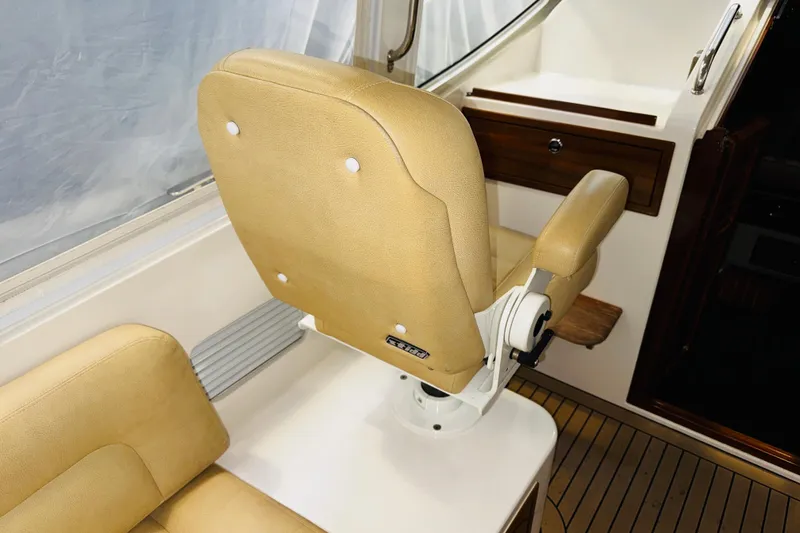 Slide: The Image of Captain's chair on 2015 MJM 36z Express boat, featuring tan upholstery and wooden accents. - 37