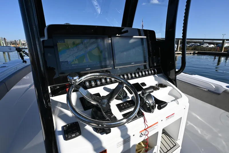 Slide: The Image of 2025 Sea Hunt Gamefish 30 Coffin Box boat dashboard with navigation screens and steering wheel. - 11