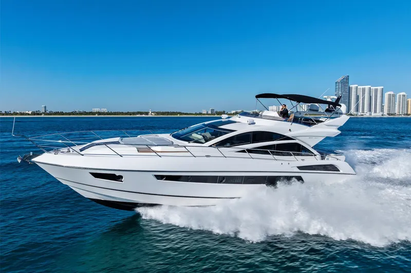 Slide: The Image of 2014 Sunseeker 68 Sport Yacht cruising on blue ocean near city skyline. - 2