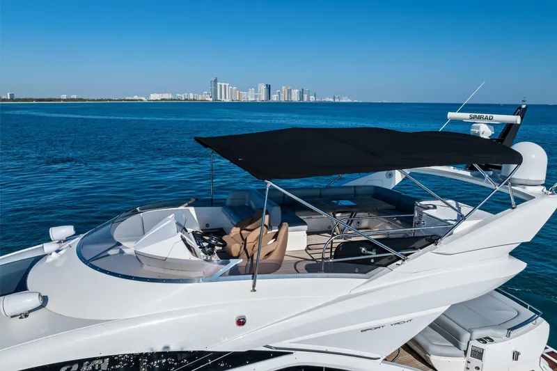 Slide: The Image of 2014 Sunseeker 68 Sport Yacht cruising on blue ocean with city skyline in background. - 3