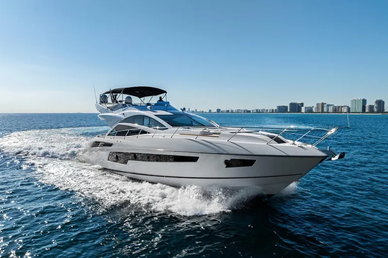 Slide: The Image of 2014 Sunseeker 68 Sport Yacht cruising on open water, city skyline in background. - 6