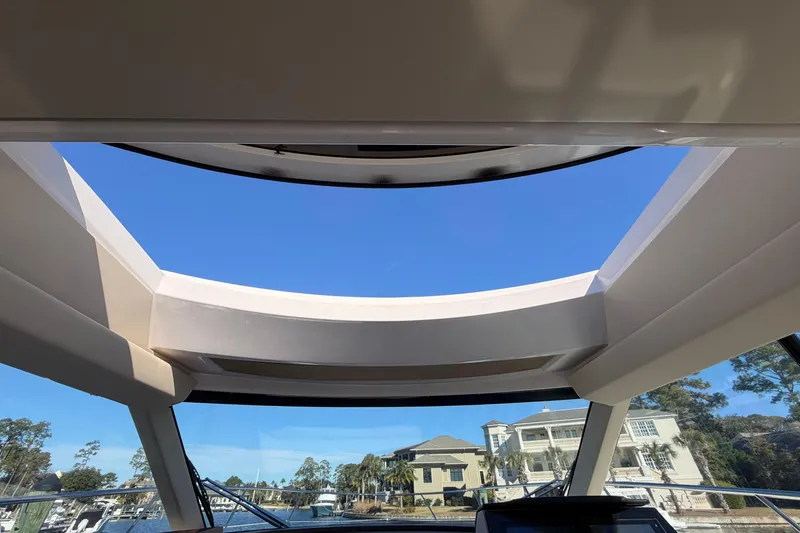Slide: The Image of 2019 Regal 42 Grande Coupe sunroof view with clear blue sky and waterfront homes. - 56