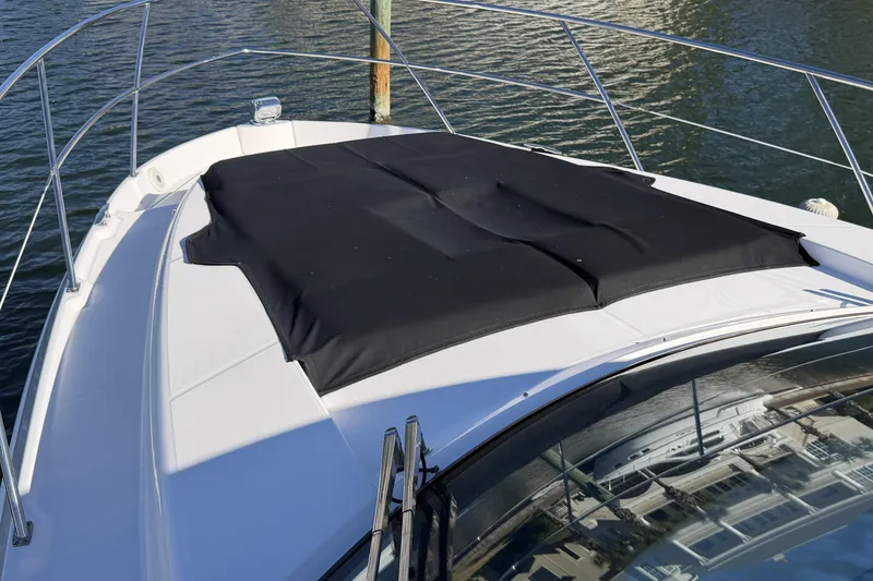 Slide: The Image of 2019 Regal 42 Grande Coupe yacht bow with black sunpad cover on water. - 8