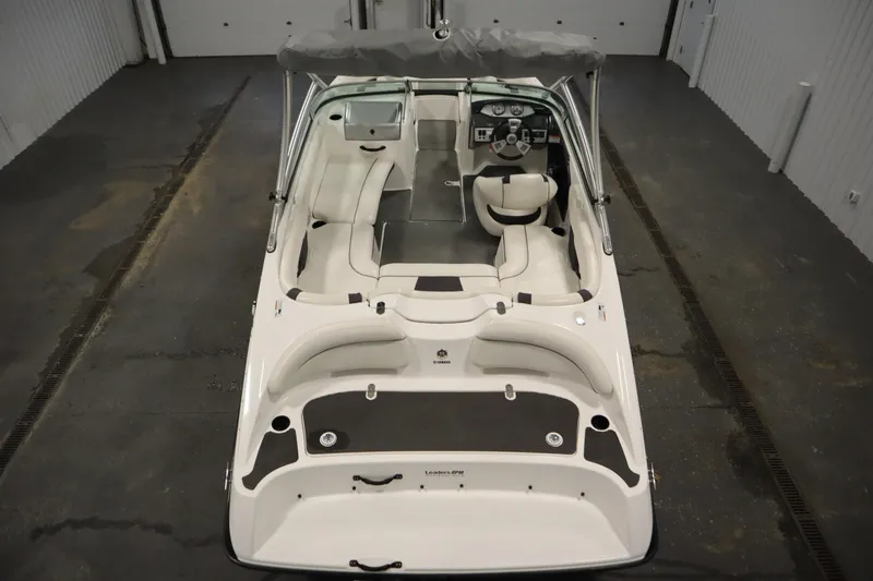 Slide: The Image of 2013 Yamaha Boats AR190, interior view, white seating, steering wheel, and canopy in a garage. - 10