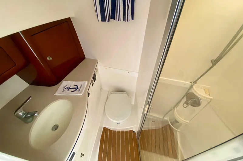 Slide: The Image of 2000 Intrepid 377 Walkaround boat bathroom with sink, toilet, and wooden cabinets. - 57