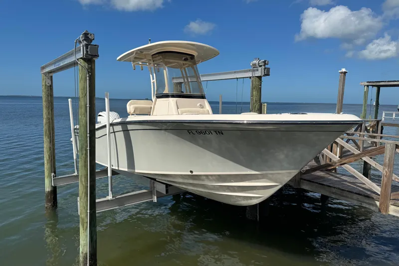 Slide: The Image of 2023 Grady-White Fisherman 236 boat on lift, docked by the water under a clear blue sky. - 2