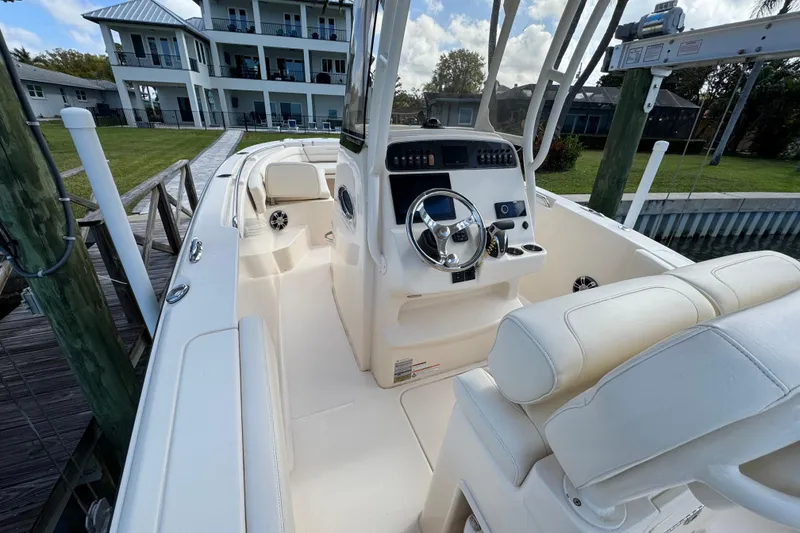 Slide: The Image of 2023 Grady-White Fisherman 236 boat interior with helm and seating, docked near waterfront homes. - 22