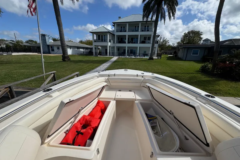 Slide: The Image of 2023 Grady-White Fisherman 236 boat with open storage compartments, docked near a large house. - 32