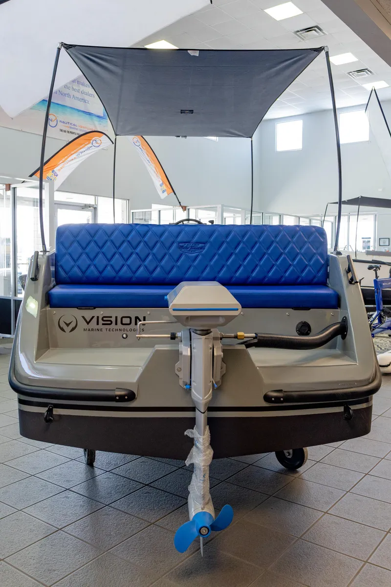 Slide: The Image of 2023 Vision Marine Technologies Volt 180 boat with blue seating and canopy in showroom. - 5