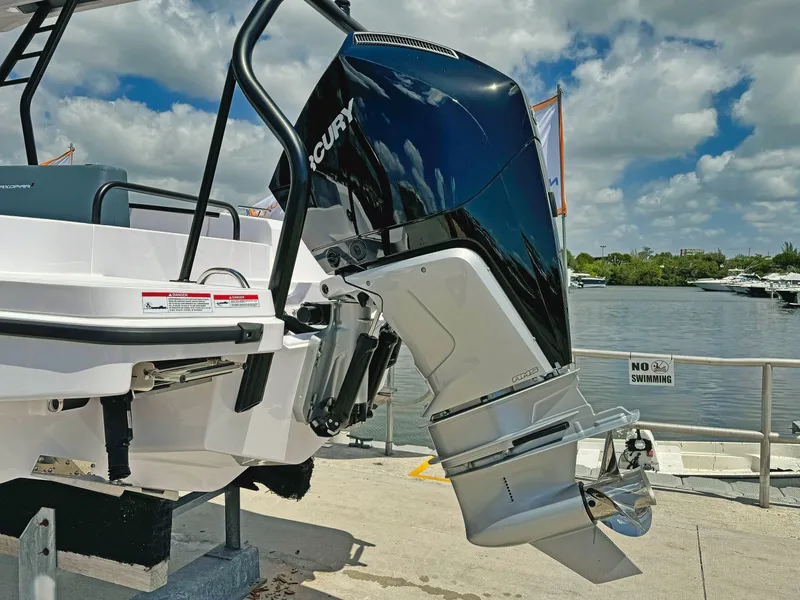 Slide: The Image of 2025 Axopar 25 Cross Top boat with powerful outboard motor, docked by a scenic waterfront. - 2