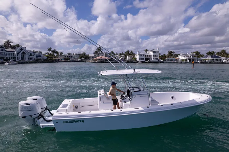 Slide: The Image of 2024 Bluewater 2550 boat cruising on a scenic waterfront with modern homes. - 10