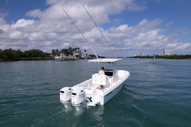 Slide: The Image of 2024 Bluewater 2550 boat cruising on a scenic waterway under a partly cloudy sky. - 12